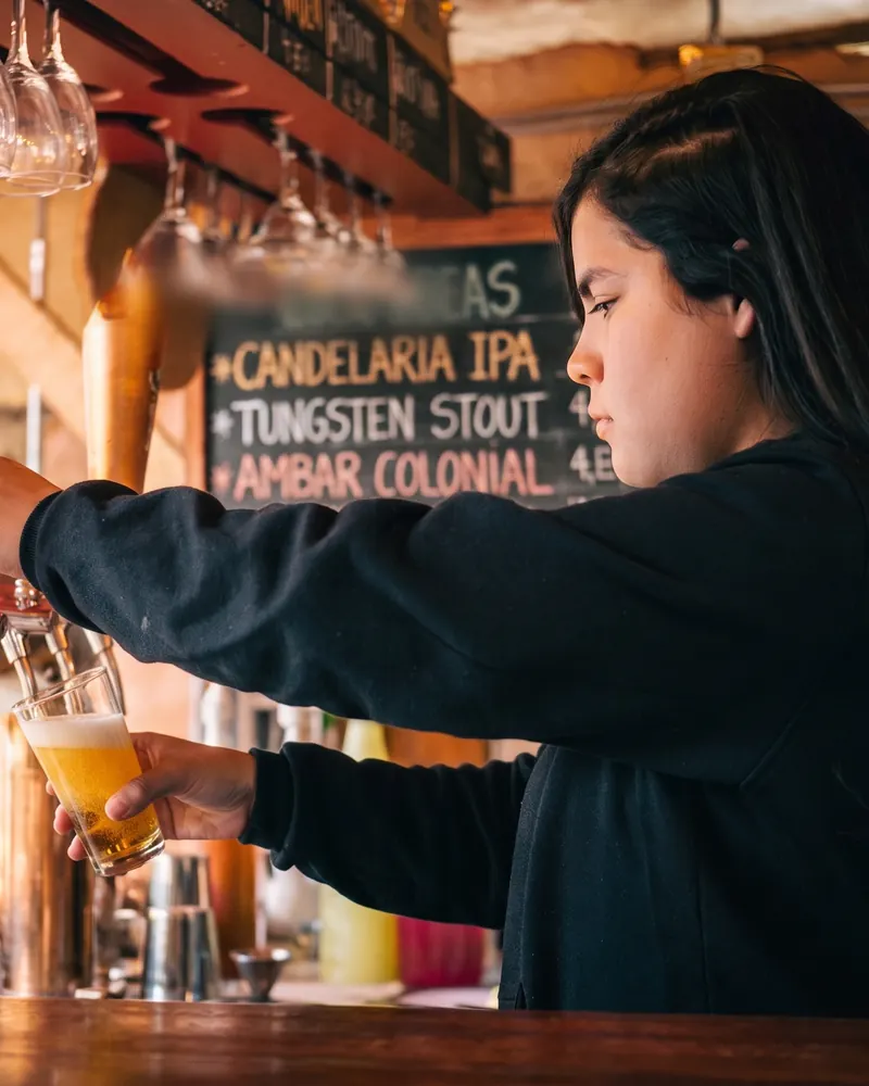 Bartender pouring a Candelaria IPA at a Bogotá craft taproom