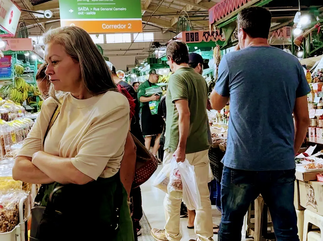 People browsing and shopping in a crowded local market during a walking tour in Curitiba, Brazil.