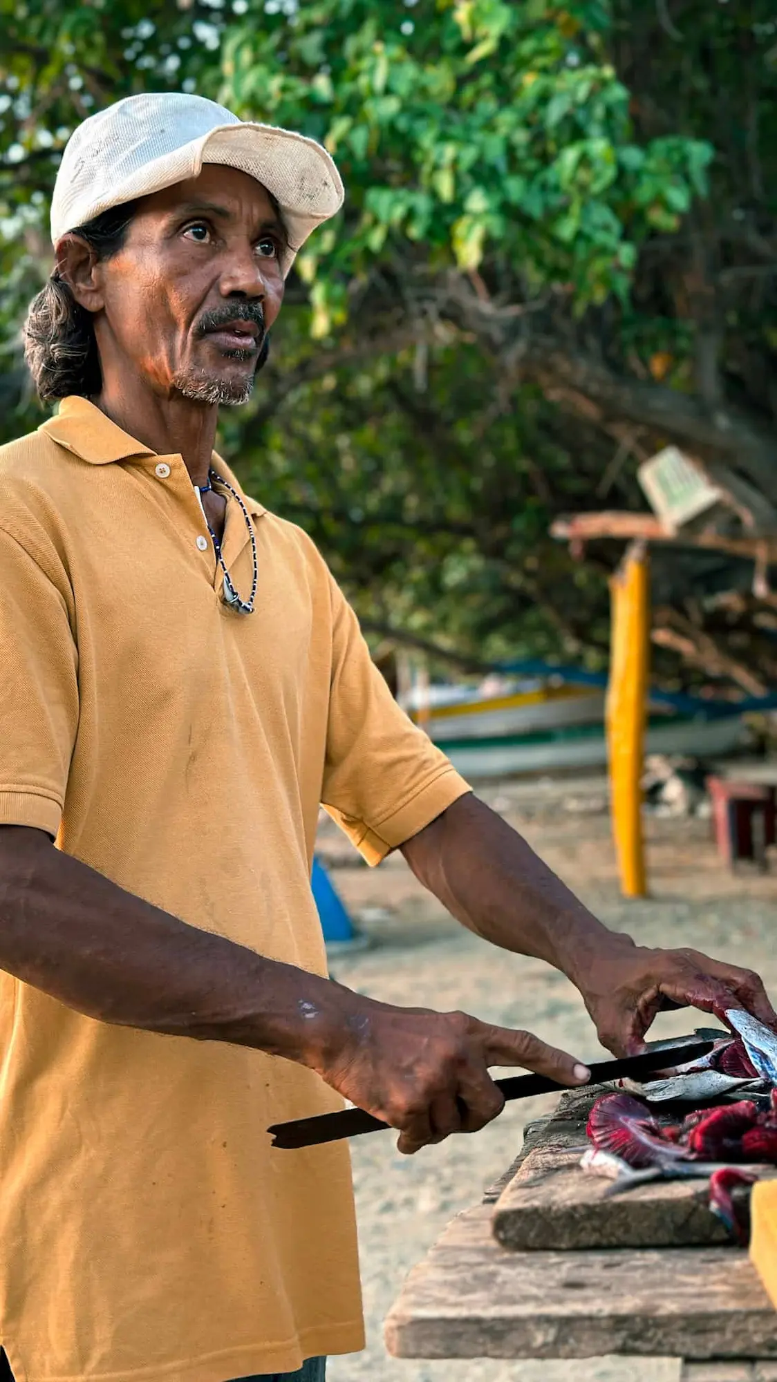 Local fisherman prepares fresh catch during Santa Marta food tour, showcasing traditional Caribbean seafood skills on the beach