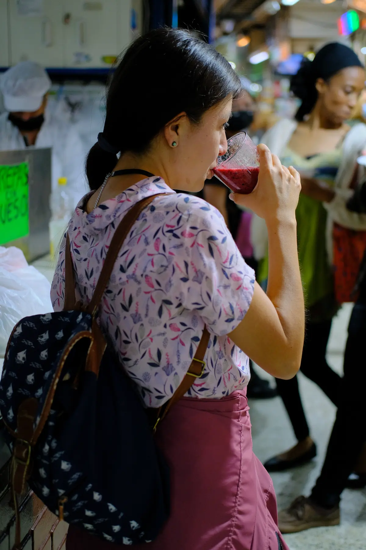 Woman enjoying a fresh fruit juice during Bogota fruit tour, surrounded by bustling market atmosphere