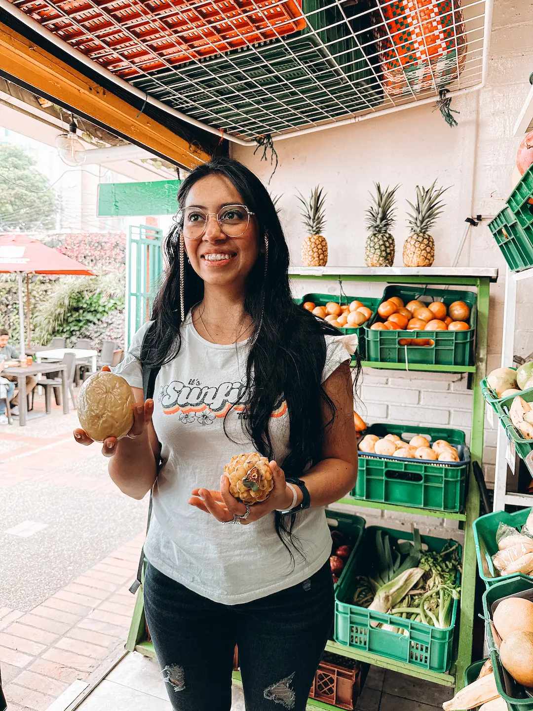 A woman holding tropical fruits in a local market in Medellin, Colombia