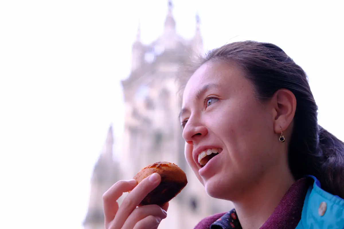 Woman enjoying a pastry during a food tour in Lourdes Chapinero, Bogota