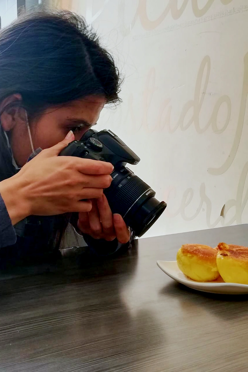 A woman taking a close-up photograph of a plate with two pastries during a food tour in Pasto, Colombia.